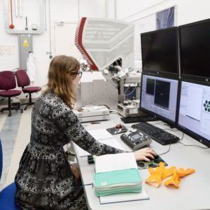A woman wearing a grey dress working with scientific equipment