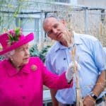 Queen Elizabeth II concentrating on a wheat plant in the greenhouse, with Phil Howell