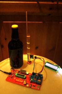 A bottle of home brewed beer together with a home made microelectronic control unit to monitor the brewing process